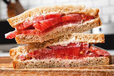 Classic tomato sandwich on a cutting board, cut diagonally and stacked