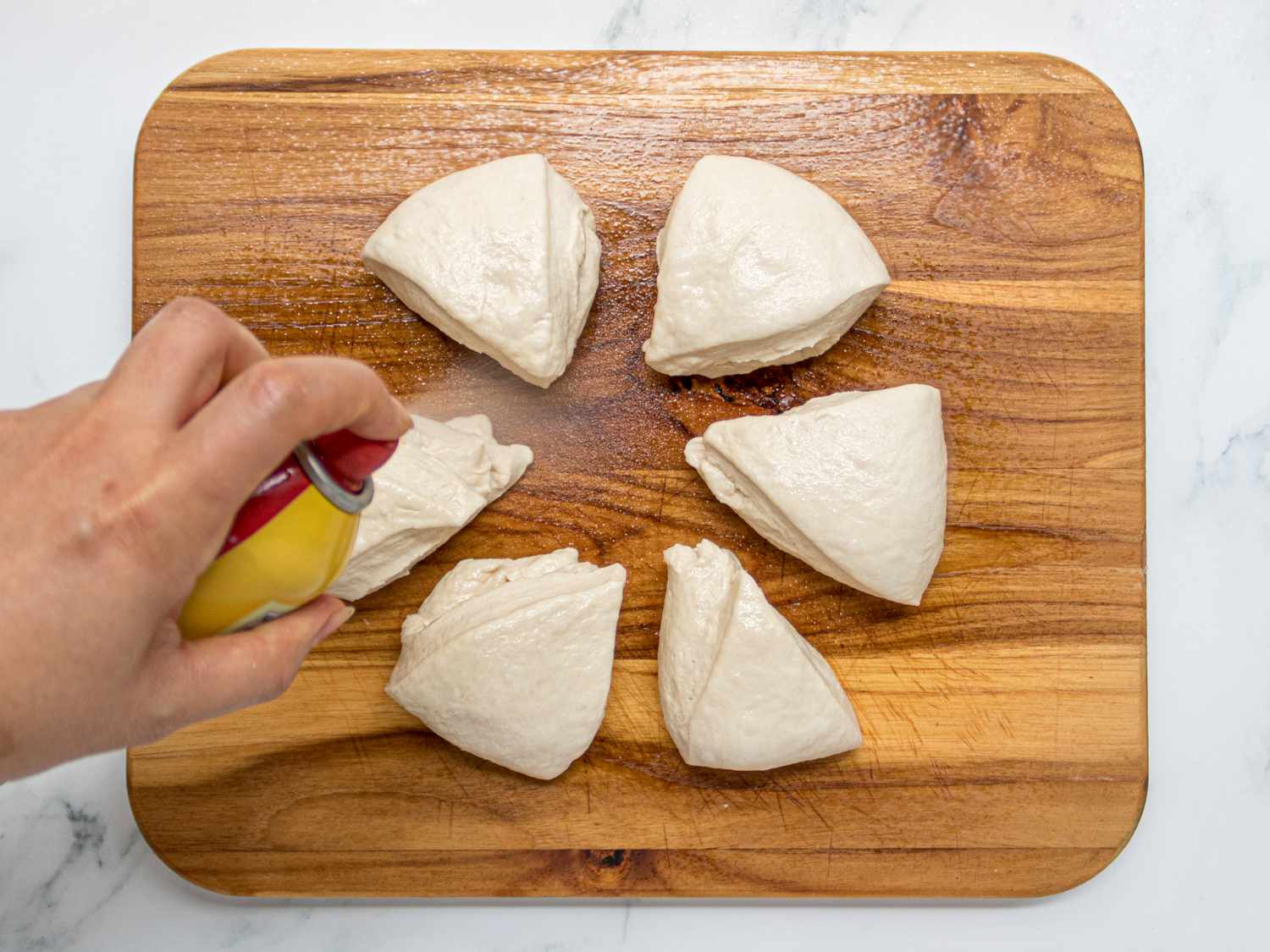 俯视of spraying dough triangles with cooking spray