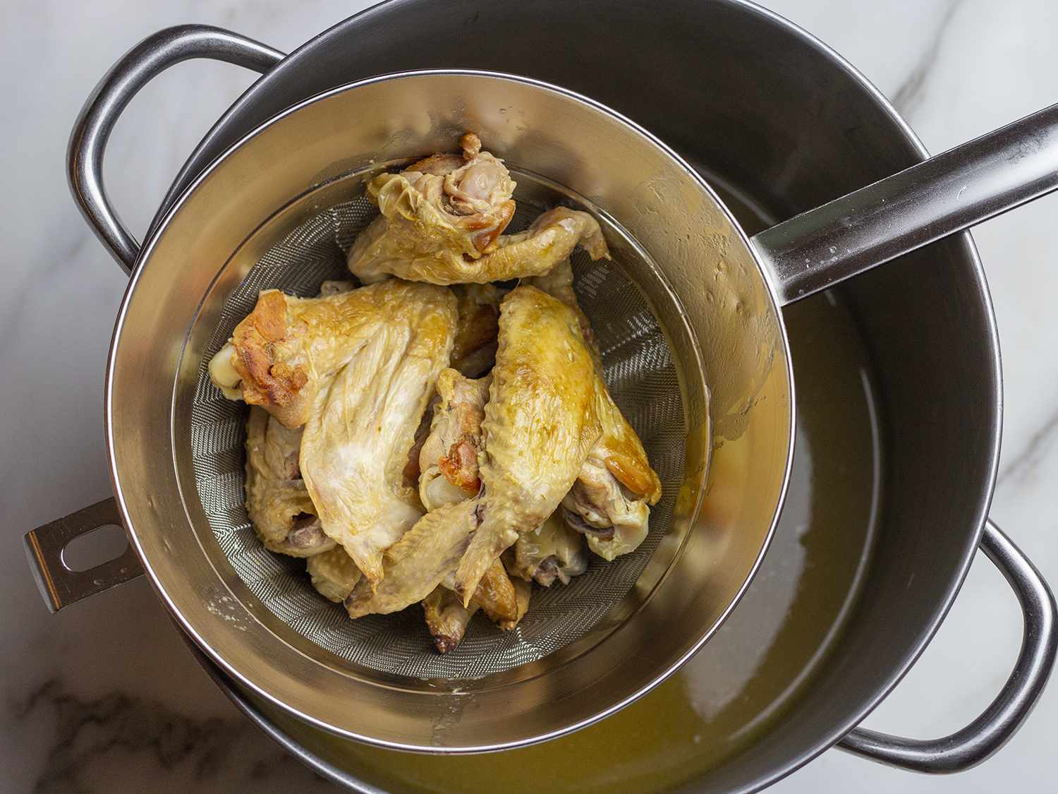 Chicken wings sitting atop a strainer.