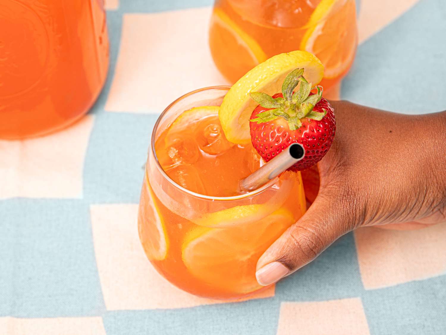 A hand grabbing a glass of strawberry lemonade