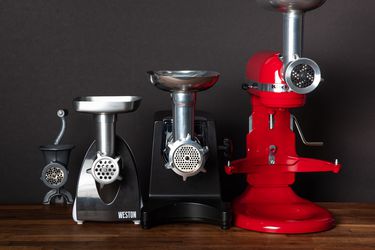 a group of meat grinders on a wooden butcher block surface