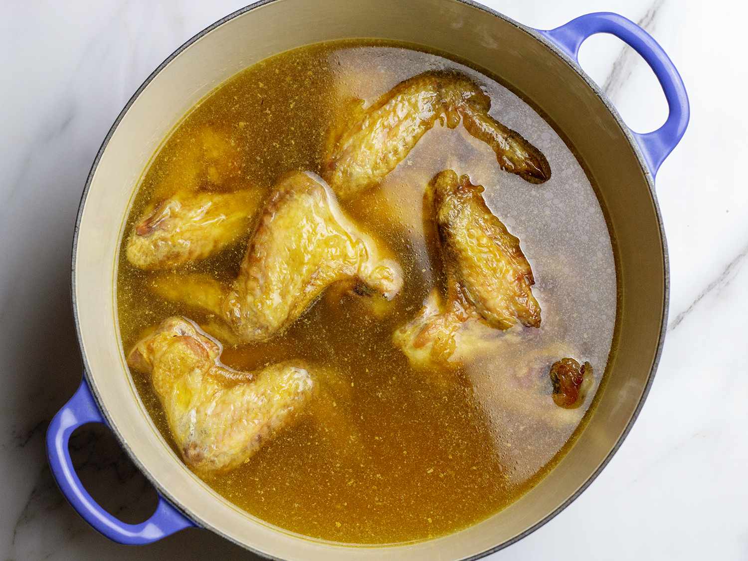 Chicken wings along with water and dissolved browned bits in a large soup pot.