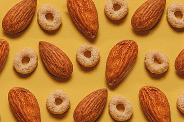 Overhead view of circle shaped cereal pieces and almonds arranged in an alternating patter