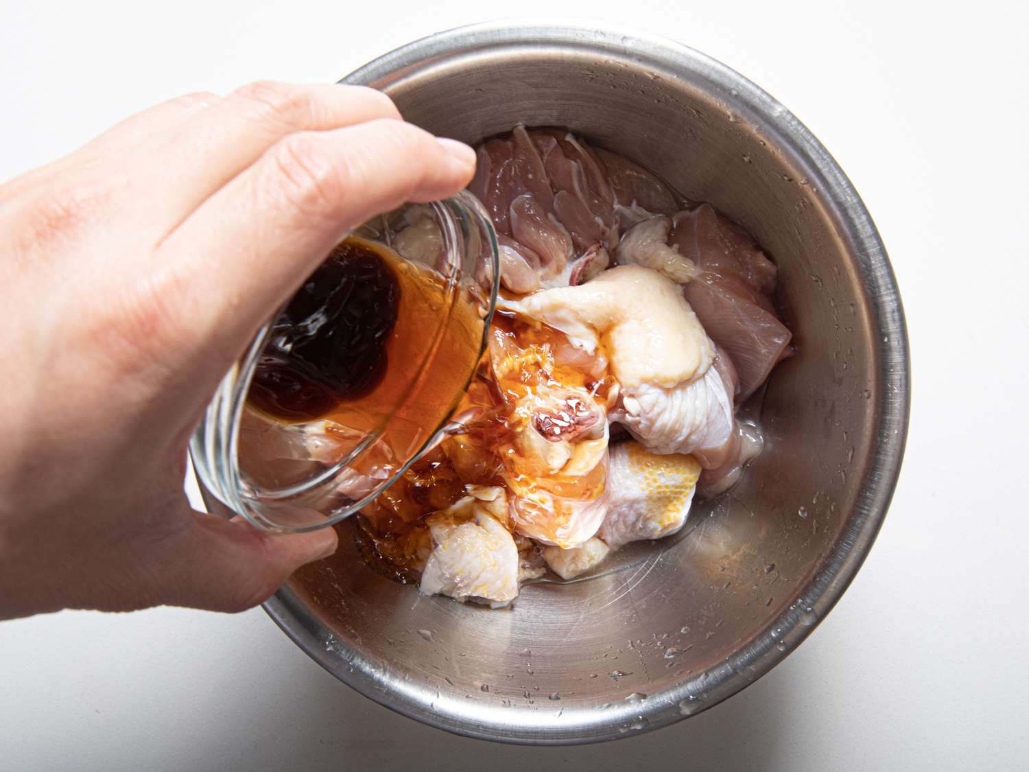 Pouring marinade onto chicken.