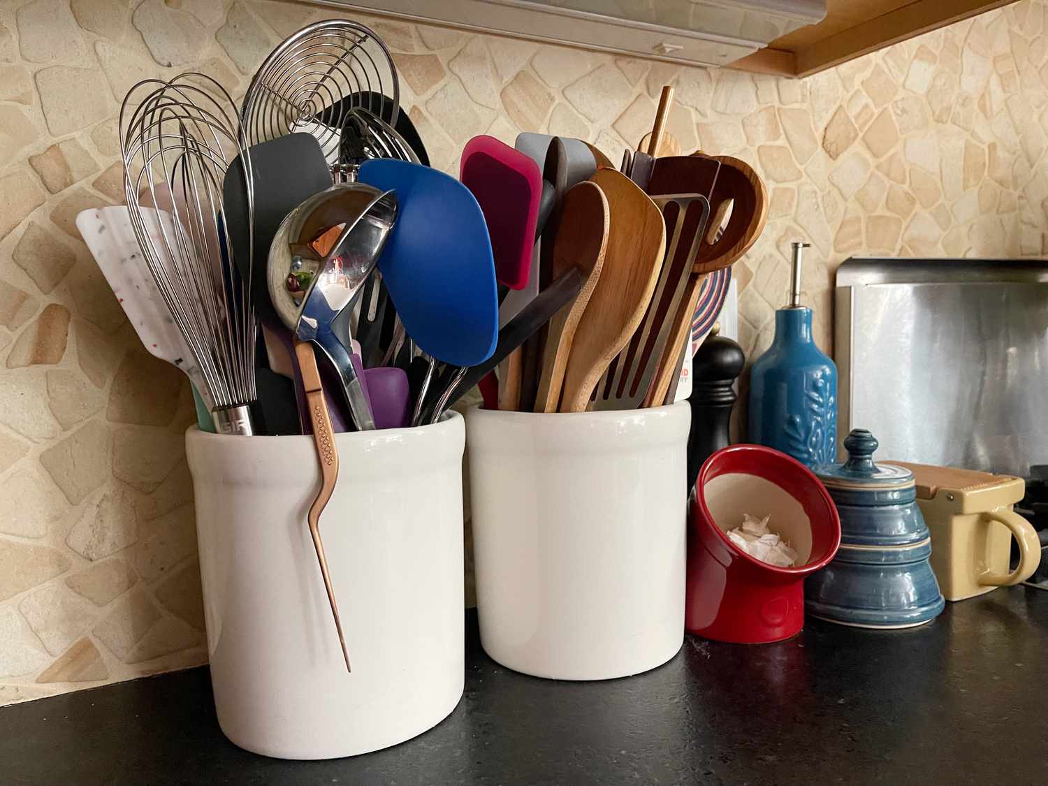 two utensil crocks filled with utensils side by side on a counter