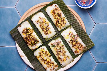 Overhead view of finished banh man on a banana leaf one a blue titled background