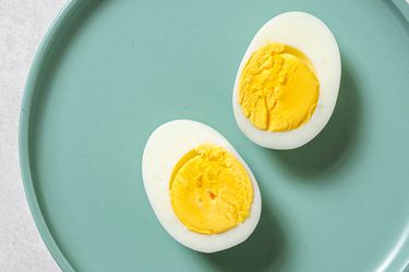 A perfect steamed boiled egg, cut in half lengthwise, on a blue plate.