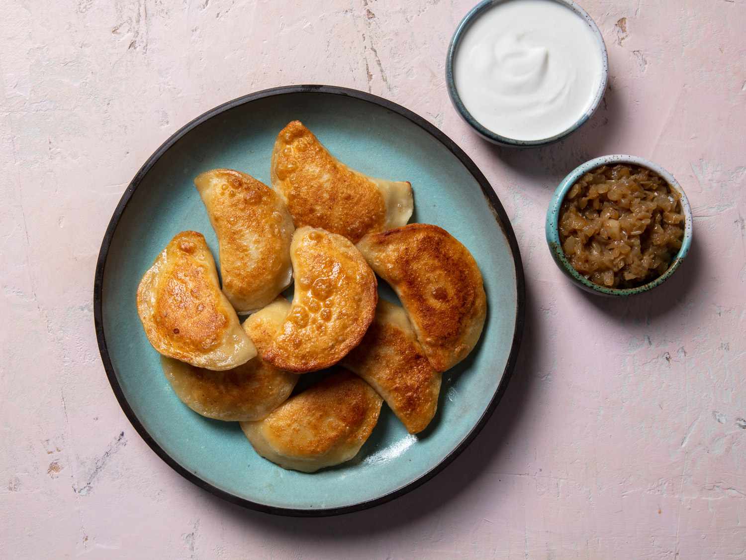 盘子的煎pierogi会后与of sour cream and cooked onion on the side.