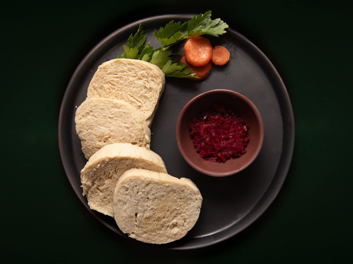 Gefilte fish displayed on a circular plate with red horseradish and garnish