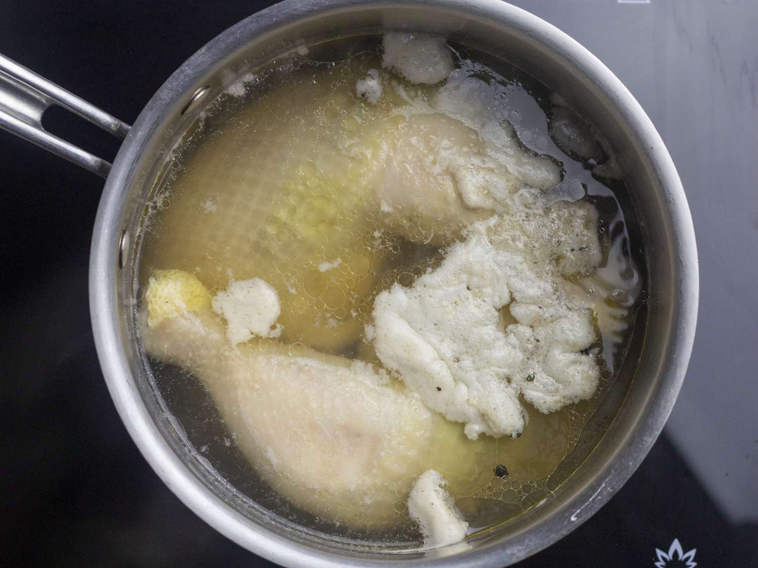 Chicken legs covered in water in a large pot.