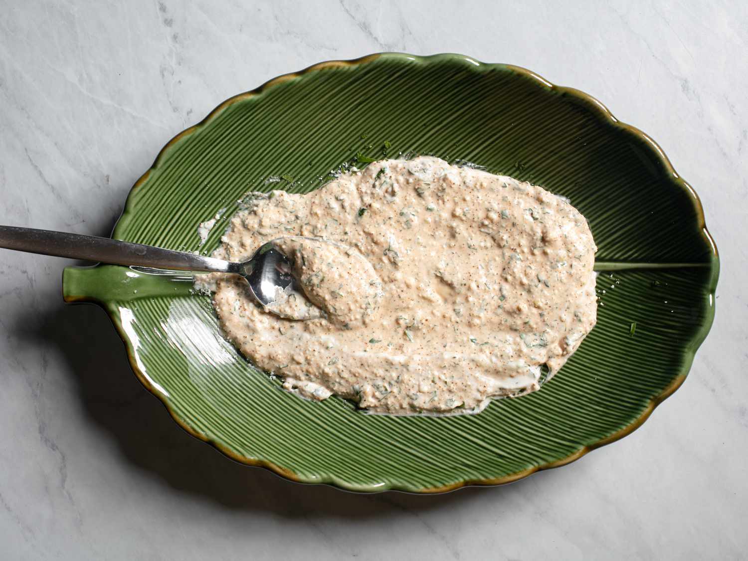 A green bowl with elotes sauce mixture