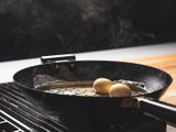 Two eggs being smoked in a wok