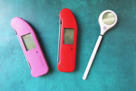 One white, one red, and one pick thermometer on a blue surface