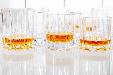 numerous rocks glasses with whiskey in them on a kitchen countertop