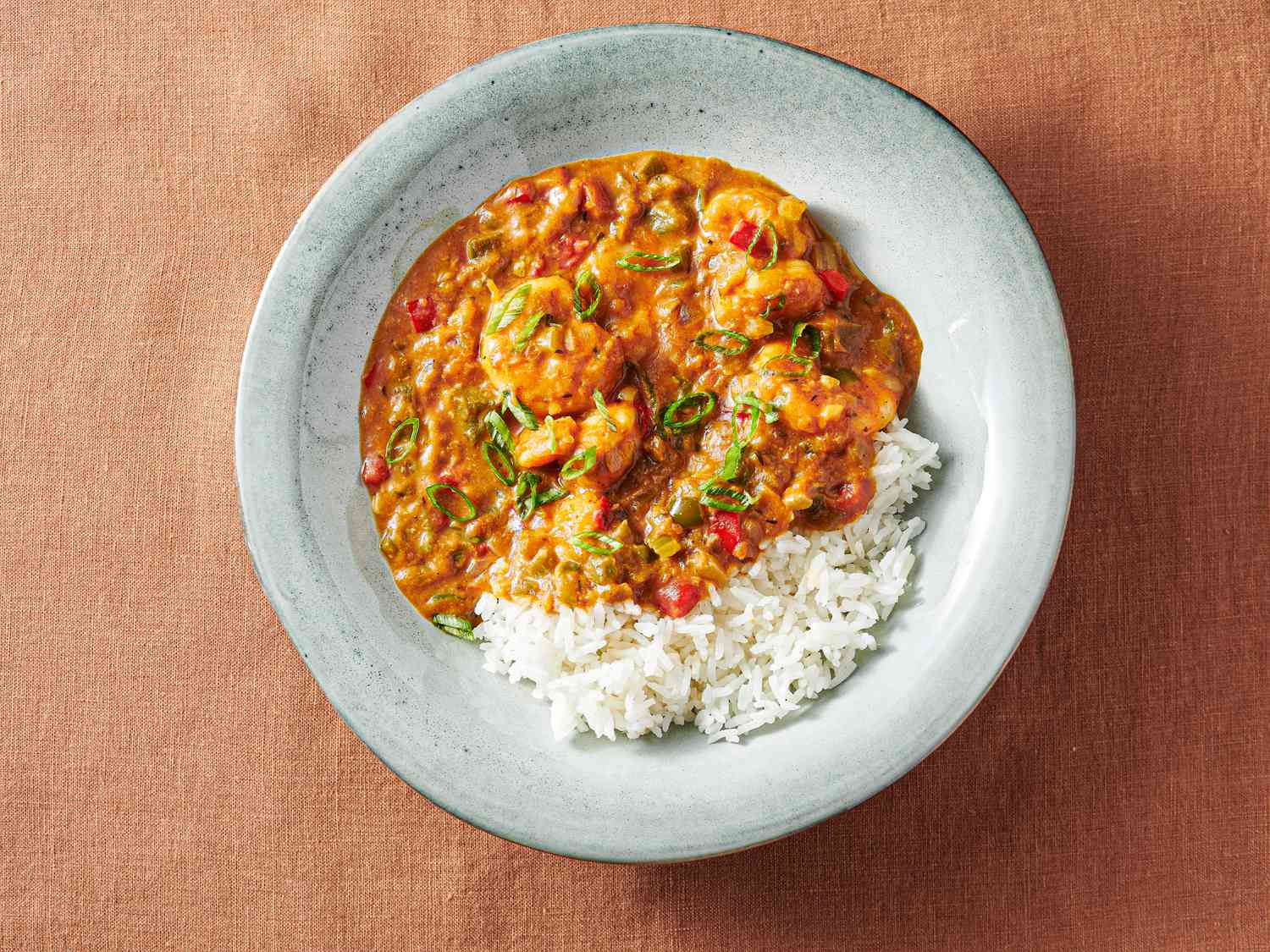 Shrimp Ã©touffÃ©e in a soup plate with rice and scallions