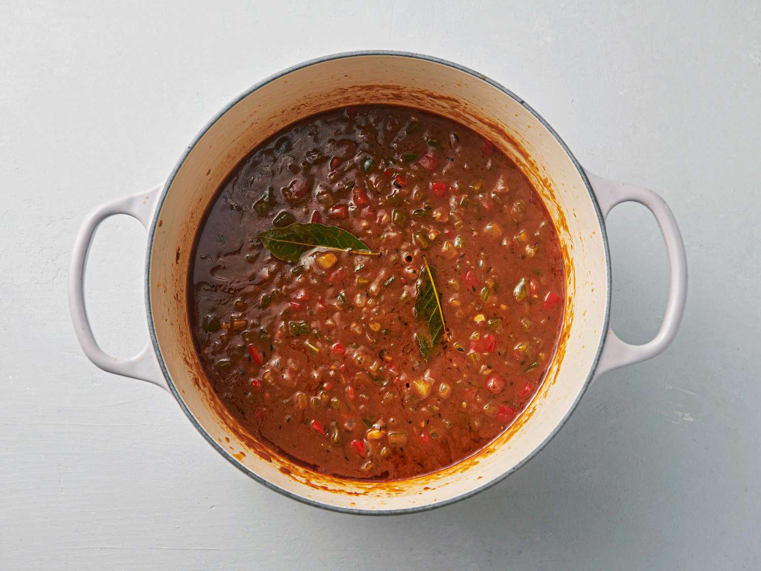 Soft vegetables inside Dutch oven, with bay leaves