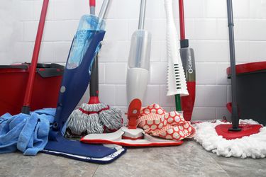 mops leaning against a white tile wall