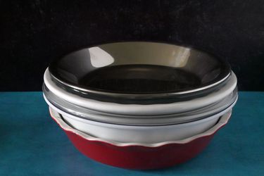 pie pans stacked together on a blue countertop with black backdrop