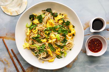 Overhead view of stir fried noodles next to sauces