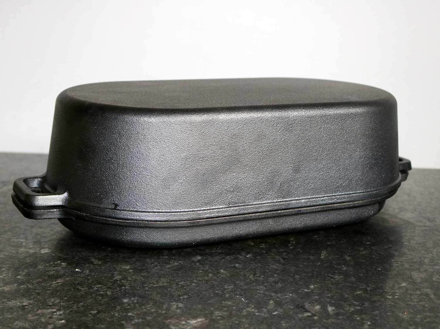 a cast iron roasting pan sits on a granite counter top