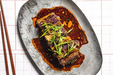 Overhead image of eggplant salad on a grey stoneware plate with chop sticks