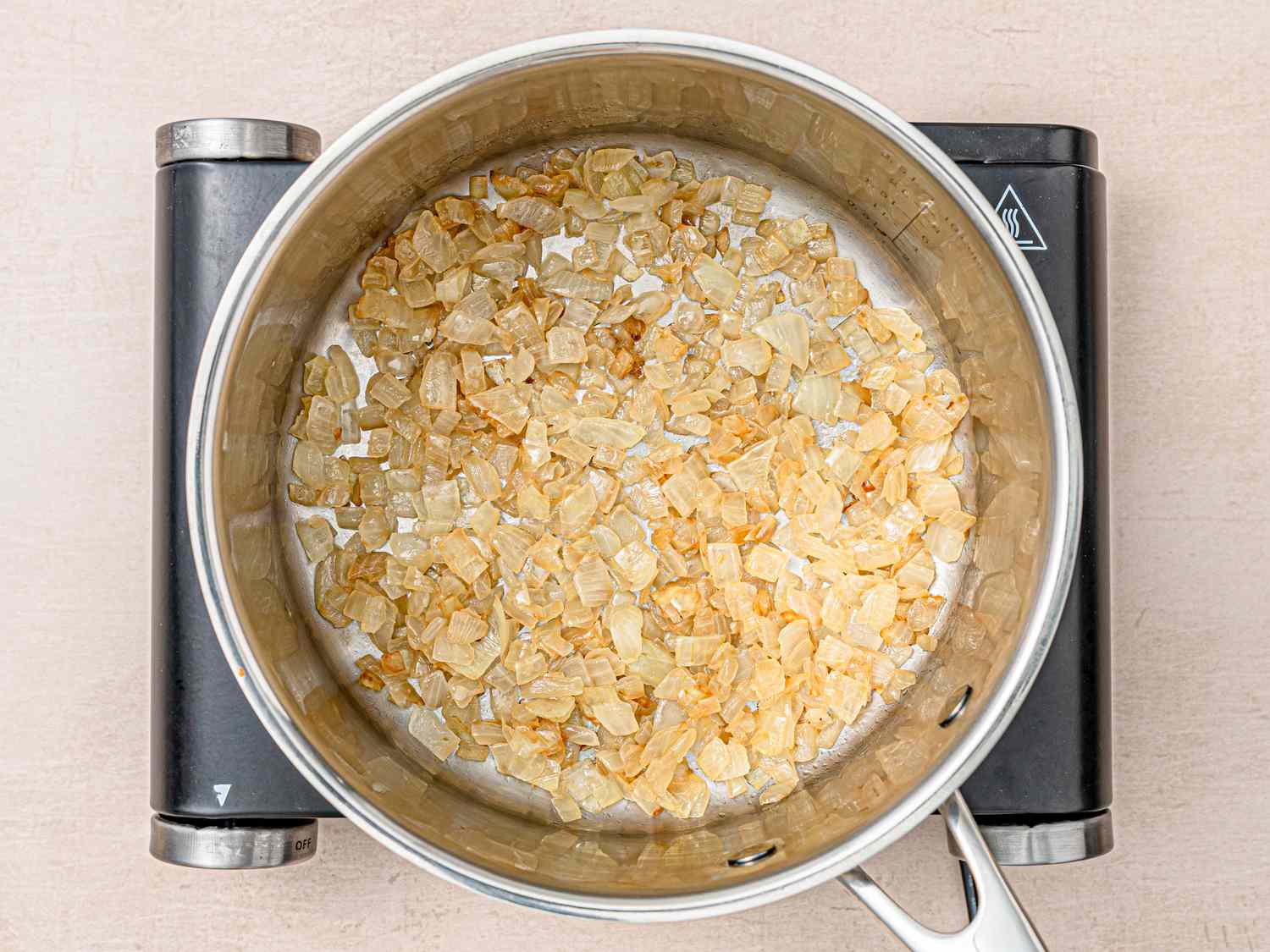 Overhead view of onions in pan cooking