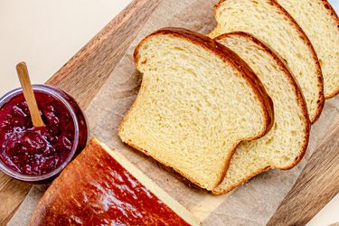 Overhead view of sliced brioche loaf on a cutting board next to jam