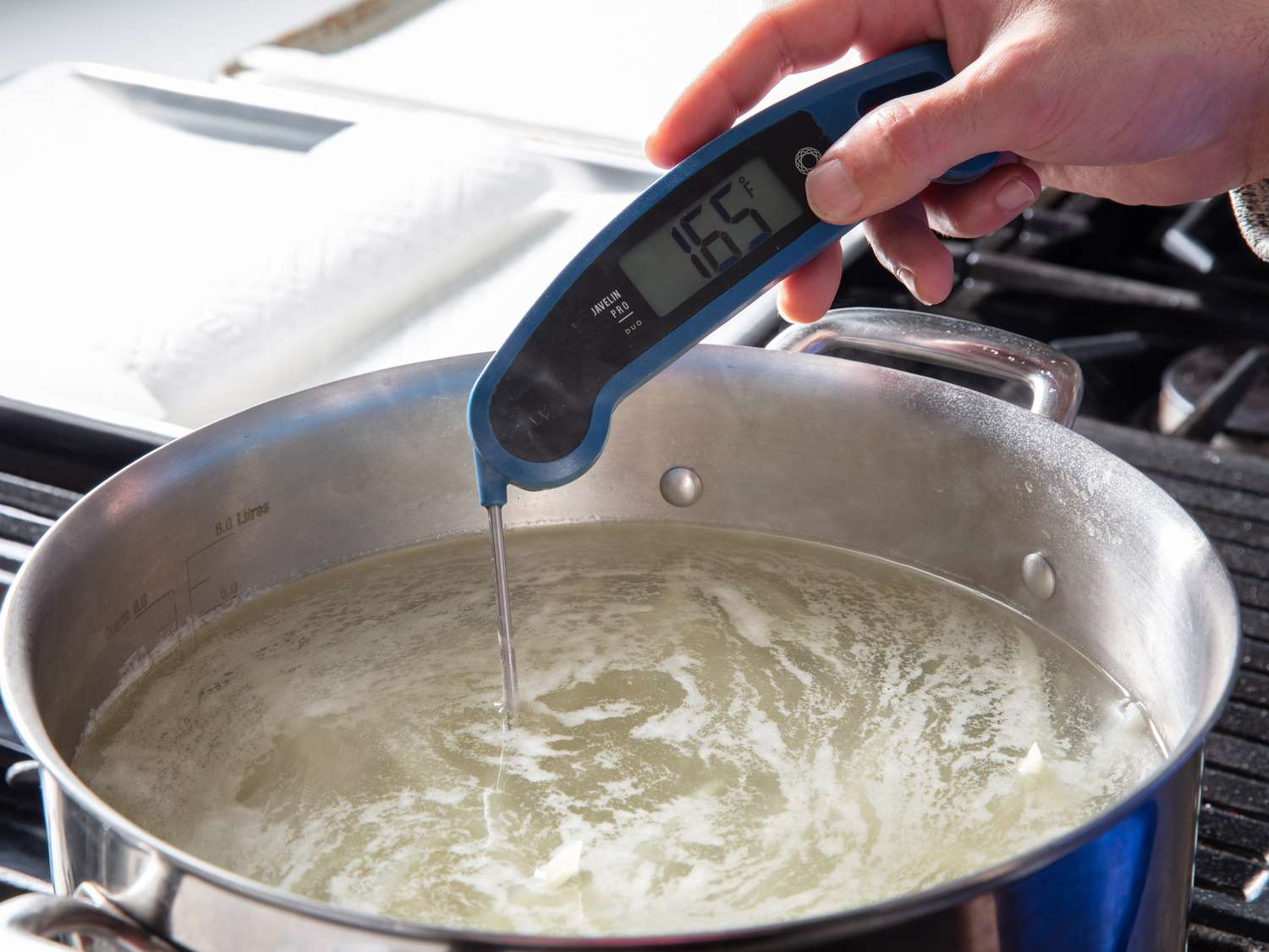 Instant read thermometer taking the temperature of a pot of salted, vinegared water with temperature reading indicating 165Â°Fahrenheit