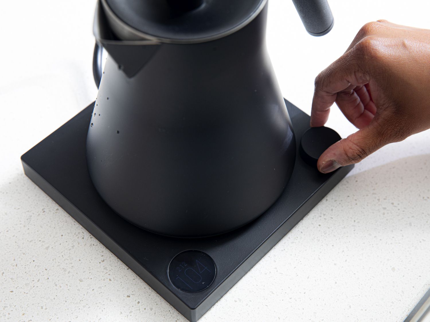 A hand turning the temperature control knob on the Fellow Corvo kettle