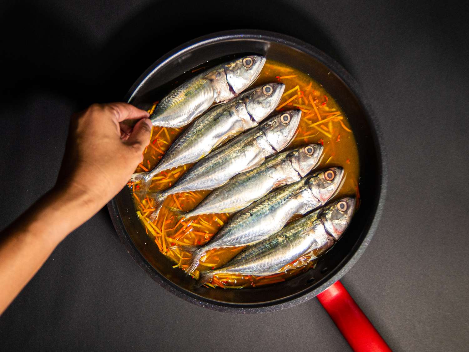 Overhead view of adding fish to pan