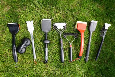 multiple grill brushes on a grassy surface