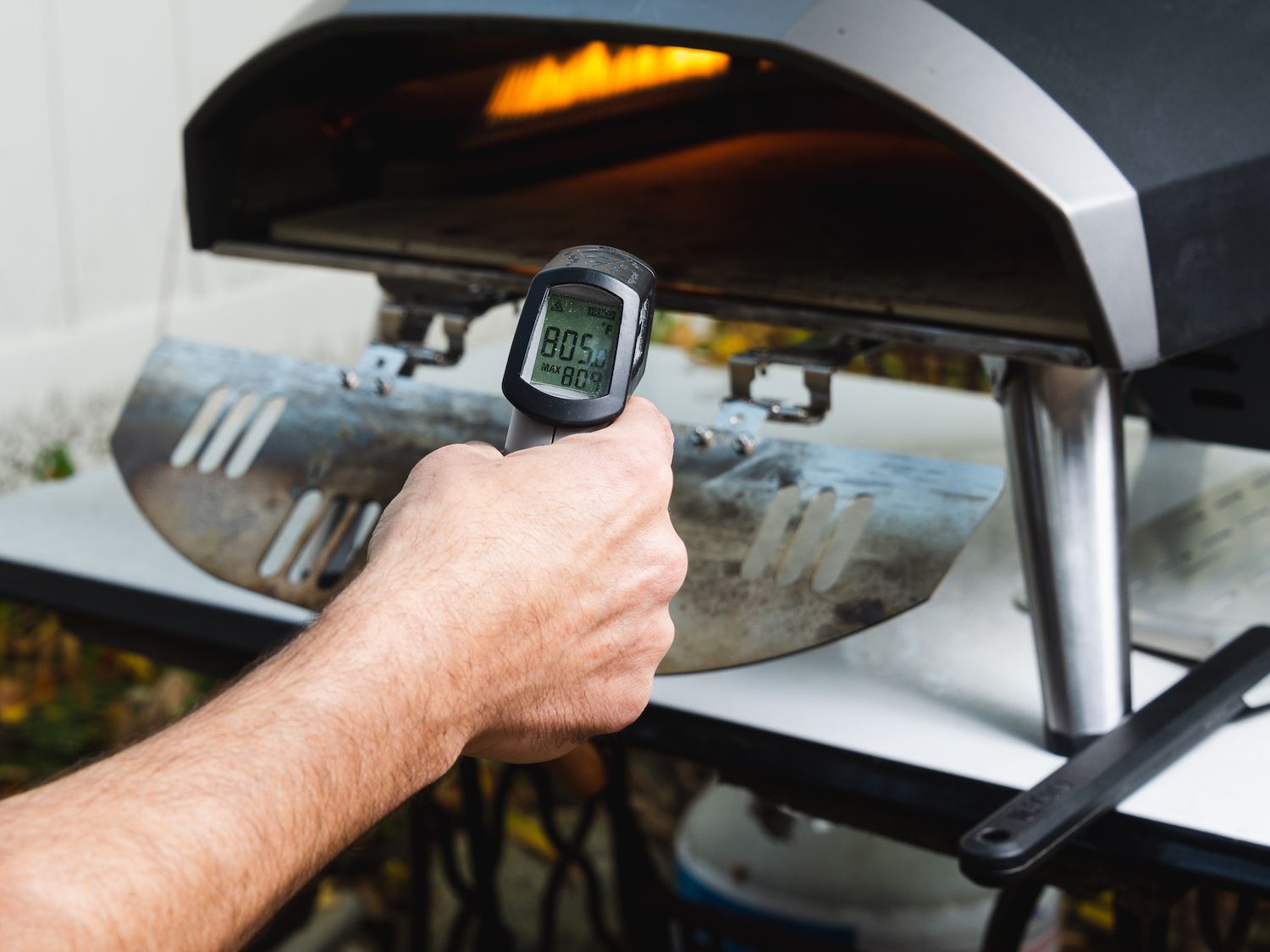 Taking the temperature of the baking surface of an outdoor pizza oven with an infrared thermometer