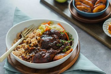 Bowl of brown stew chicken and rice and peas