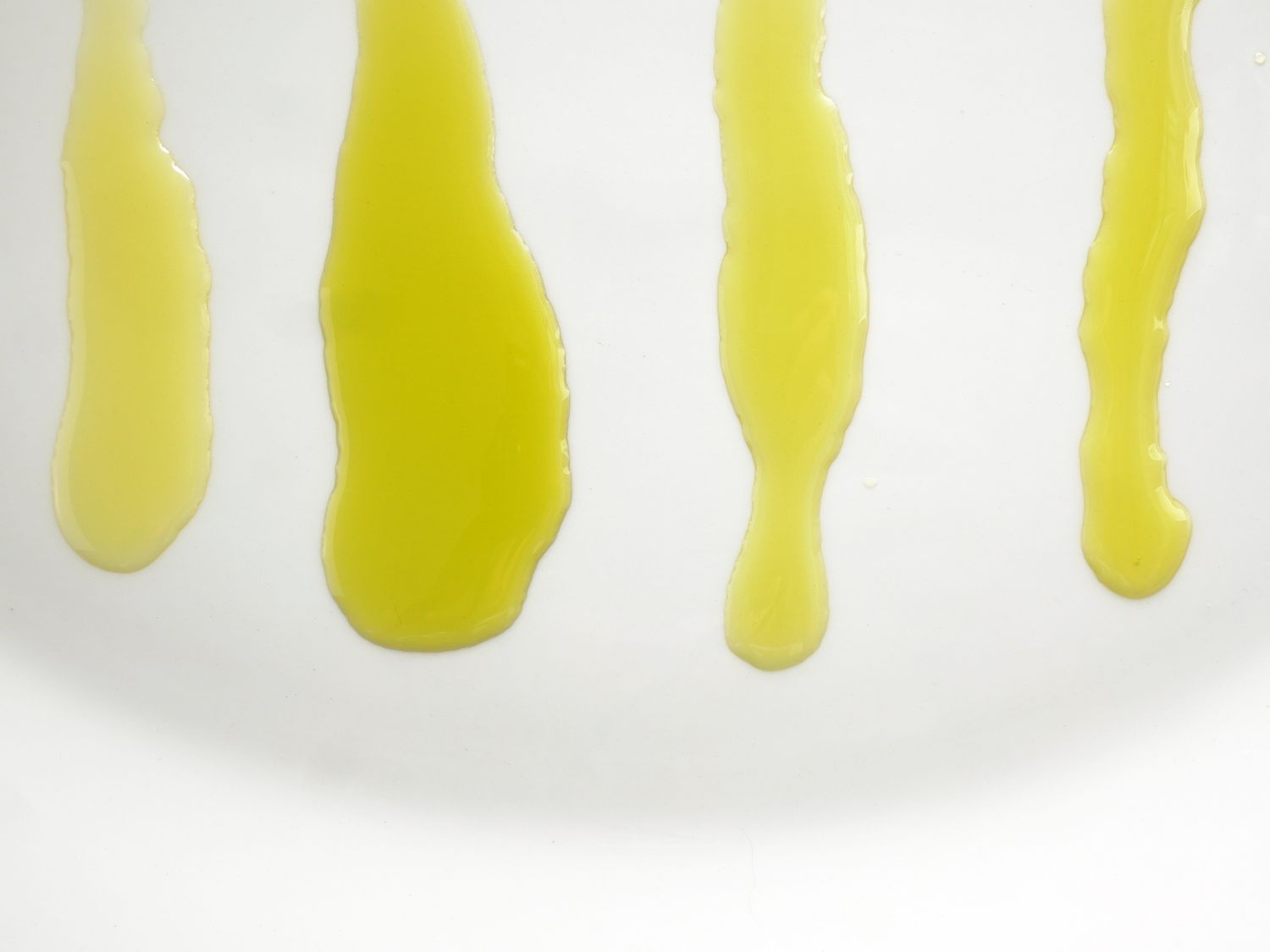 four different kinds of extra virgin olive oil on a white plate