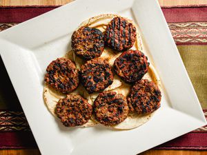 Overhead view of losh kebabs on pita on a white plate on a nicely textured, striped fabric