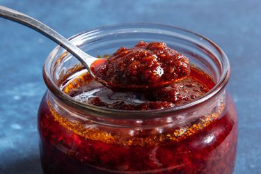 A spoonful of nam prik pao being lifted out of a jar.