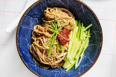 Sesame Noodles with chili paste, cucumbers, and scallions in a blue bow with a wavy patterm