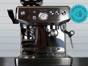 an espresso machine with a built-in grinder sits on a counter in front of a tiled wall