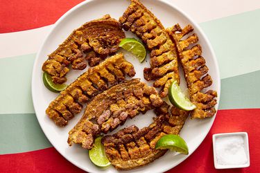 在head view of chicharrones on a plate with a small bowl of salt off to the side