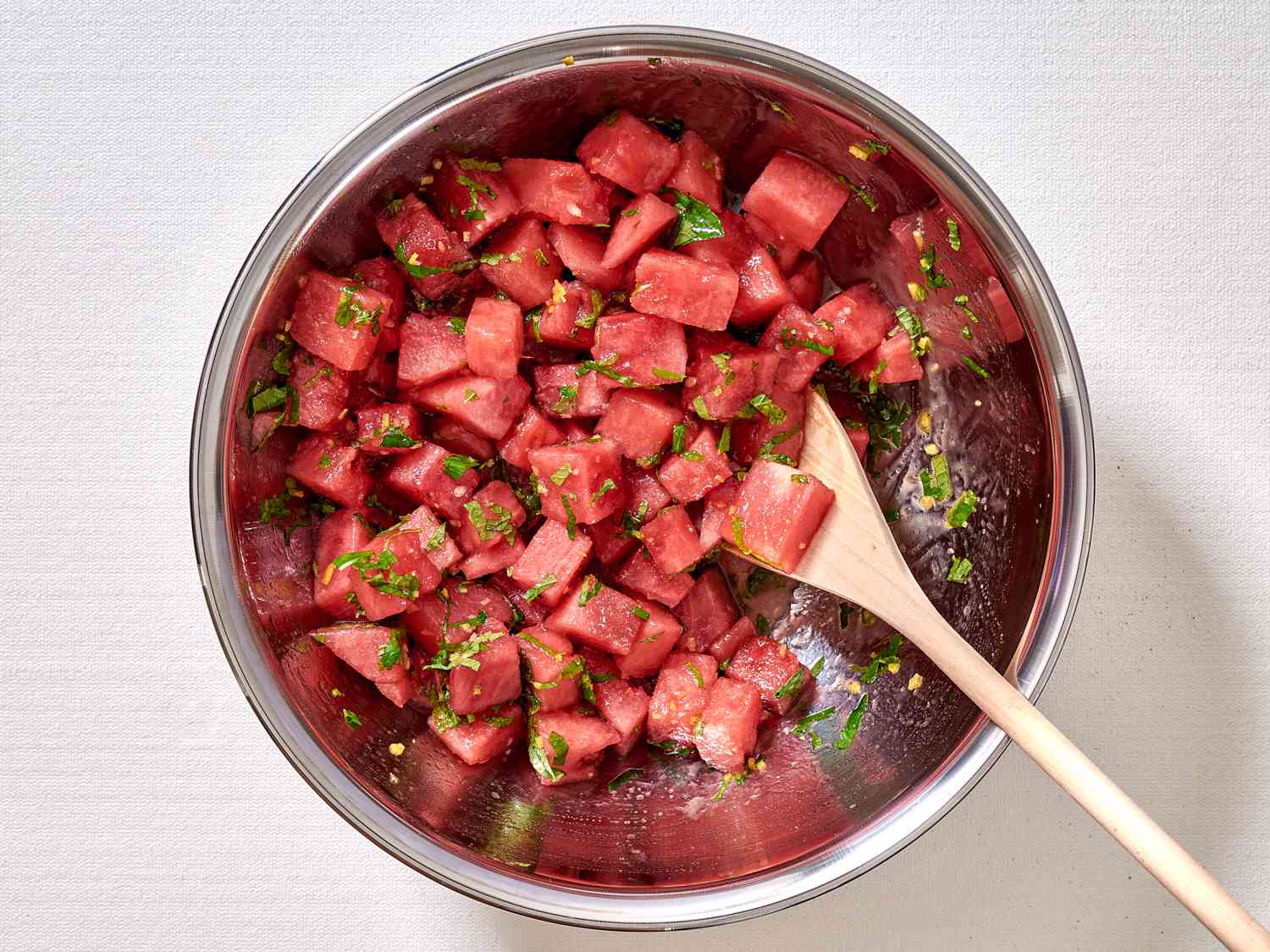 A bowl of watermelon pieces tossed with lemon juice, zest, mint, and olive oil.