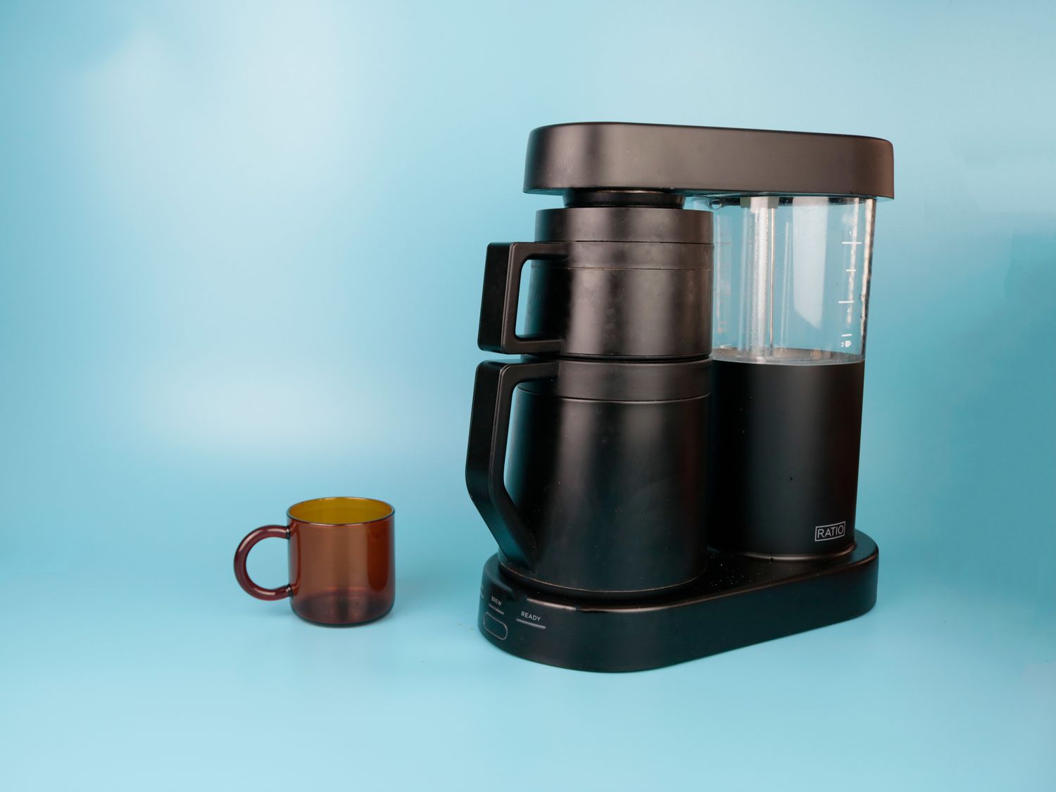 a glass mug next to a coffee brewer