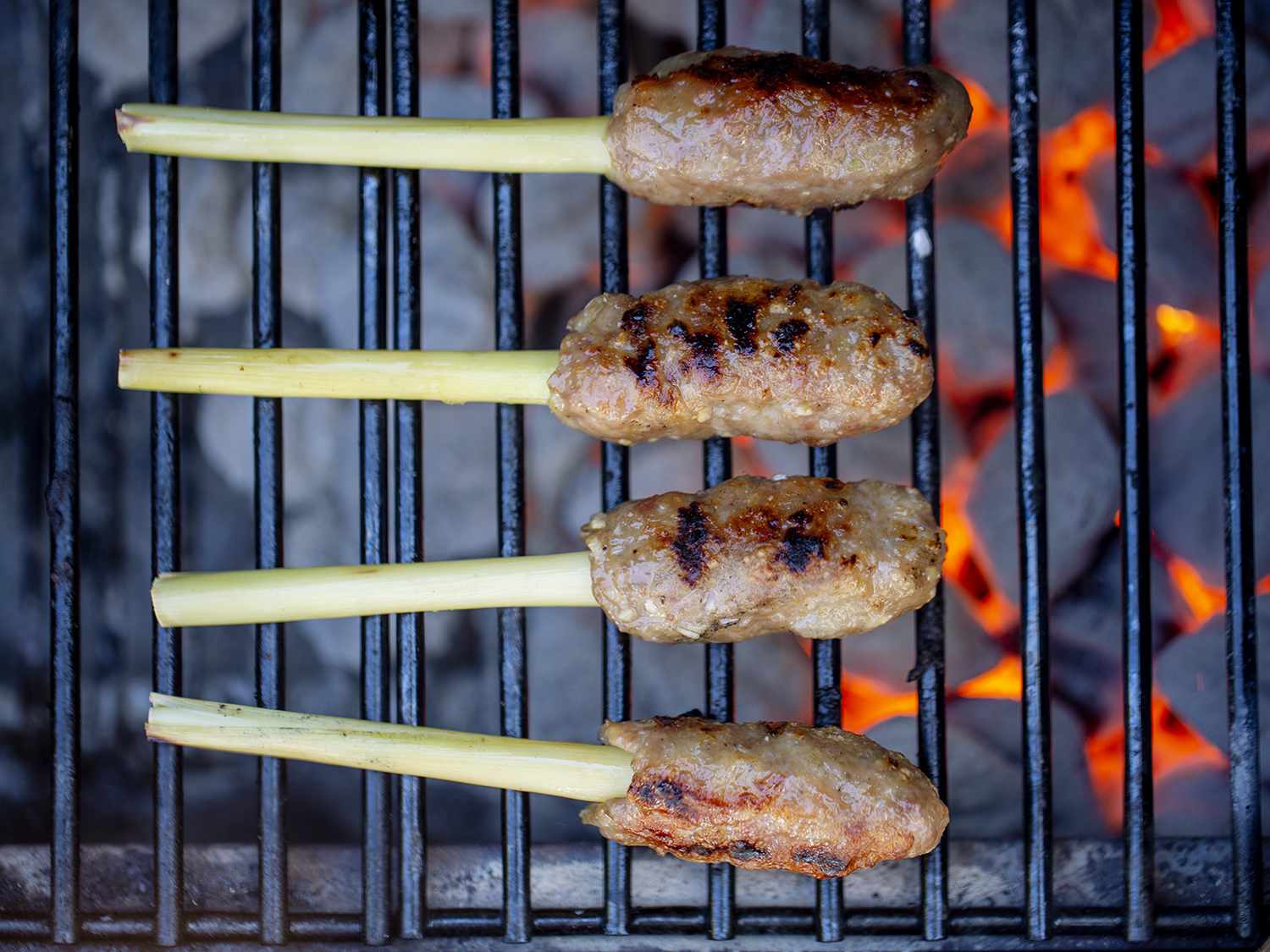 Nem lui (ground pork molded on a lemongrass stalk) being cooked over charcoal