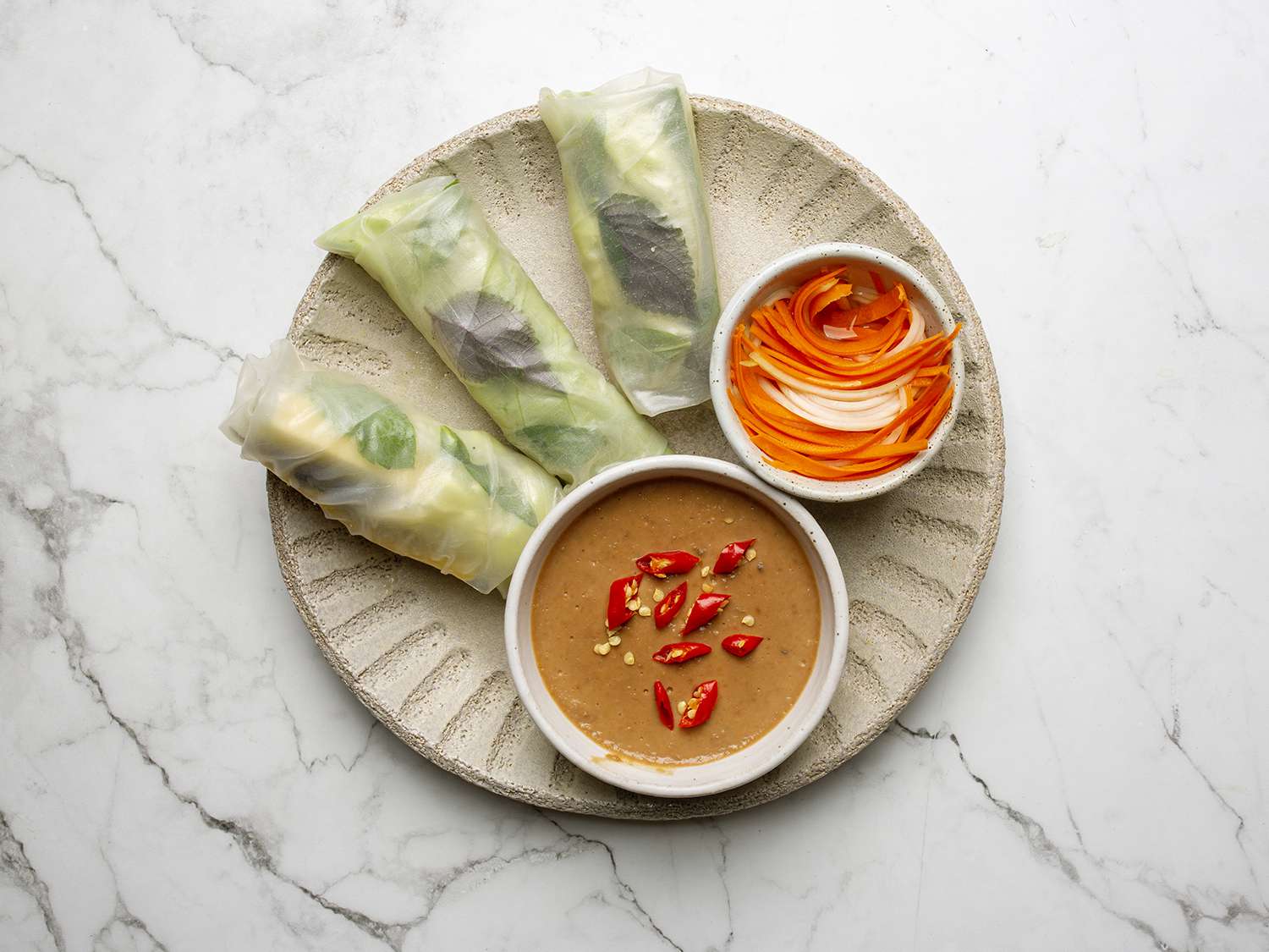 Overhead view of rice paper rolls with a bowl of dipping sauce and garnishes