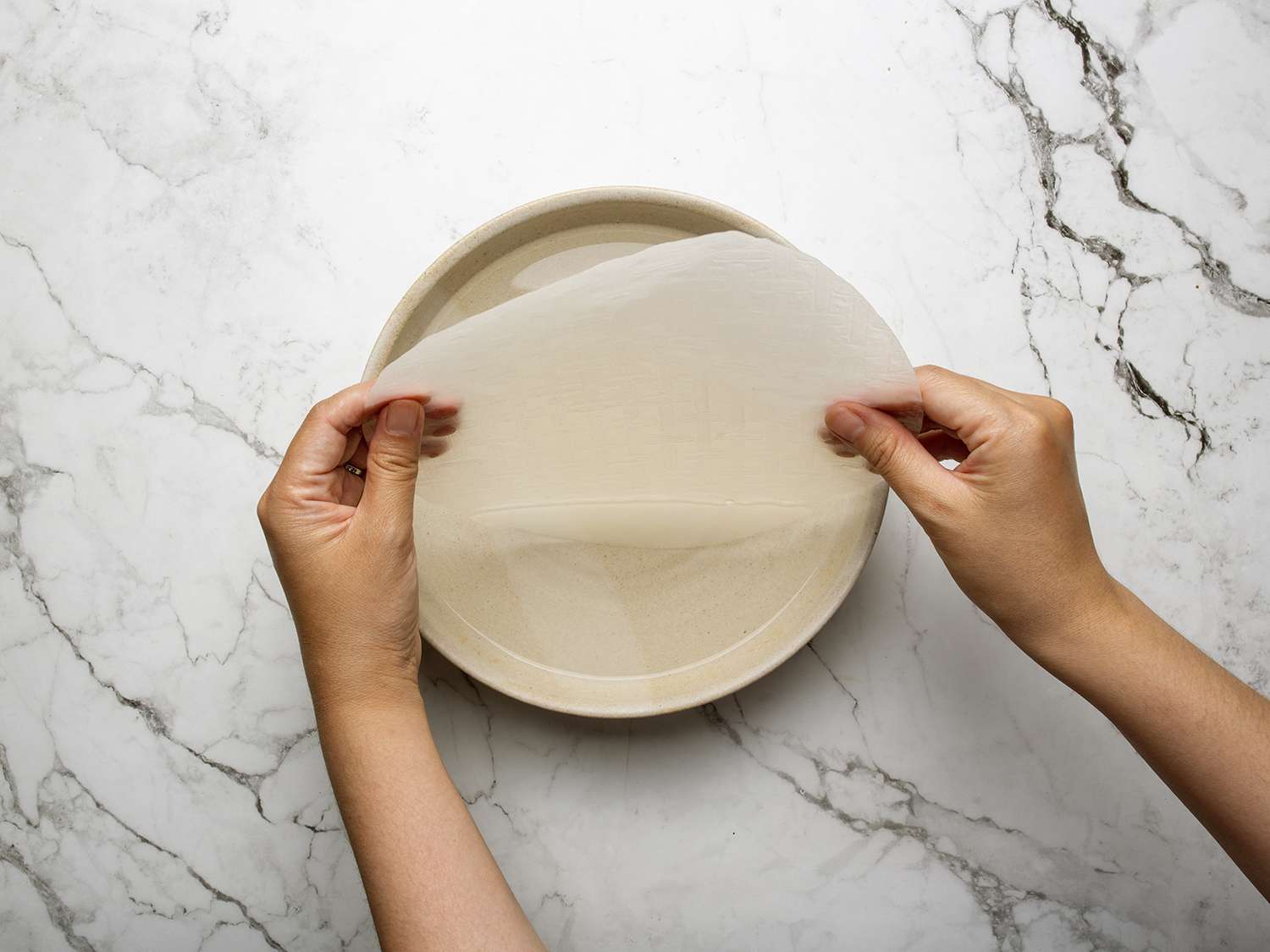 Overhead view of rice paper being dipped in water