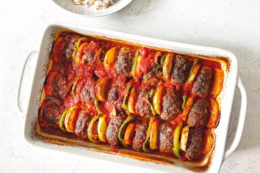 Overhead view of kafta in baking dish next to a bowl of rice.