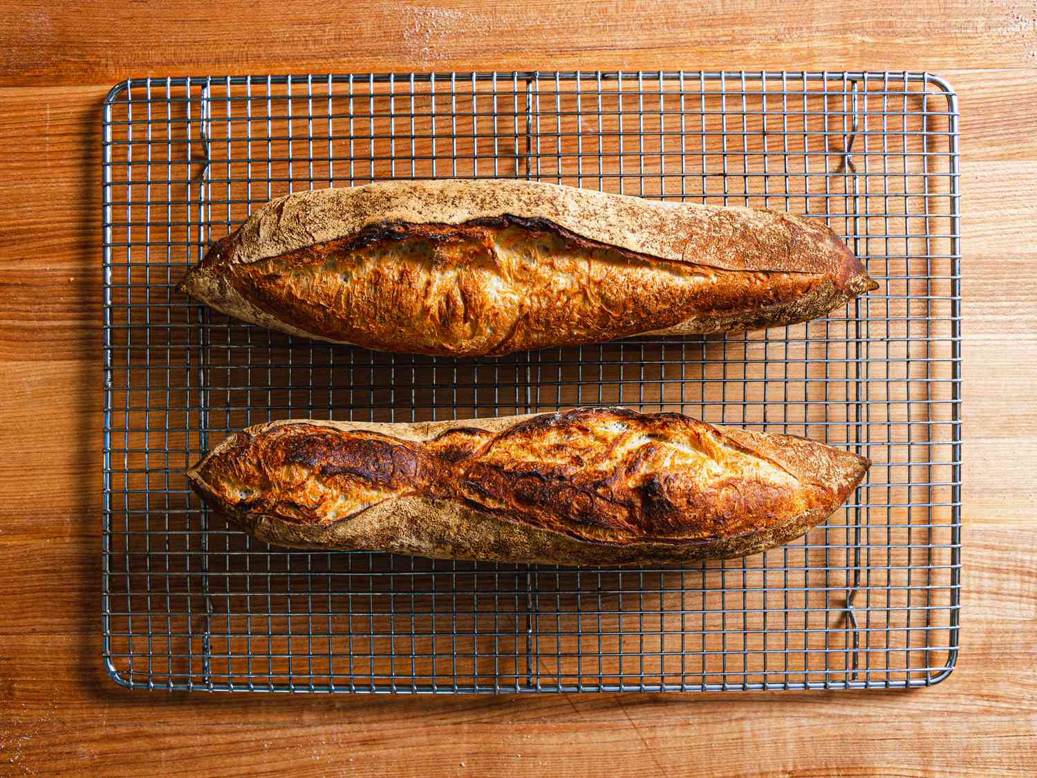 Two baguettes resting on a wire rack