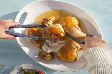 Carving a chicken on a white platter