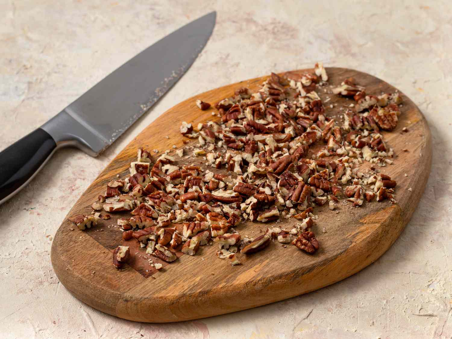 Pecans roughly chopped on a wooden cutting board.