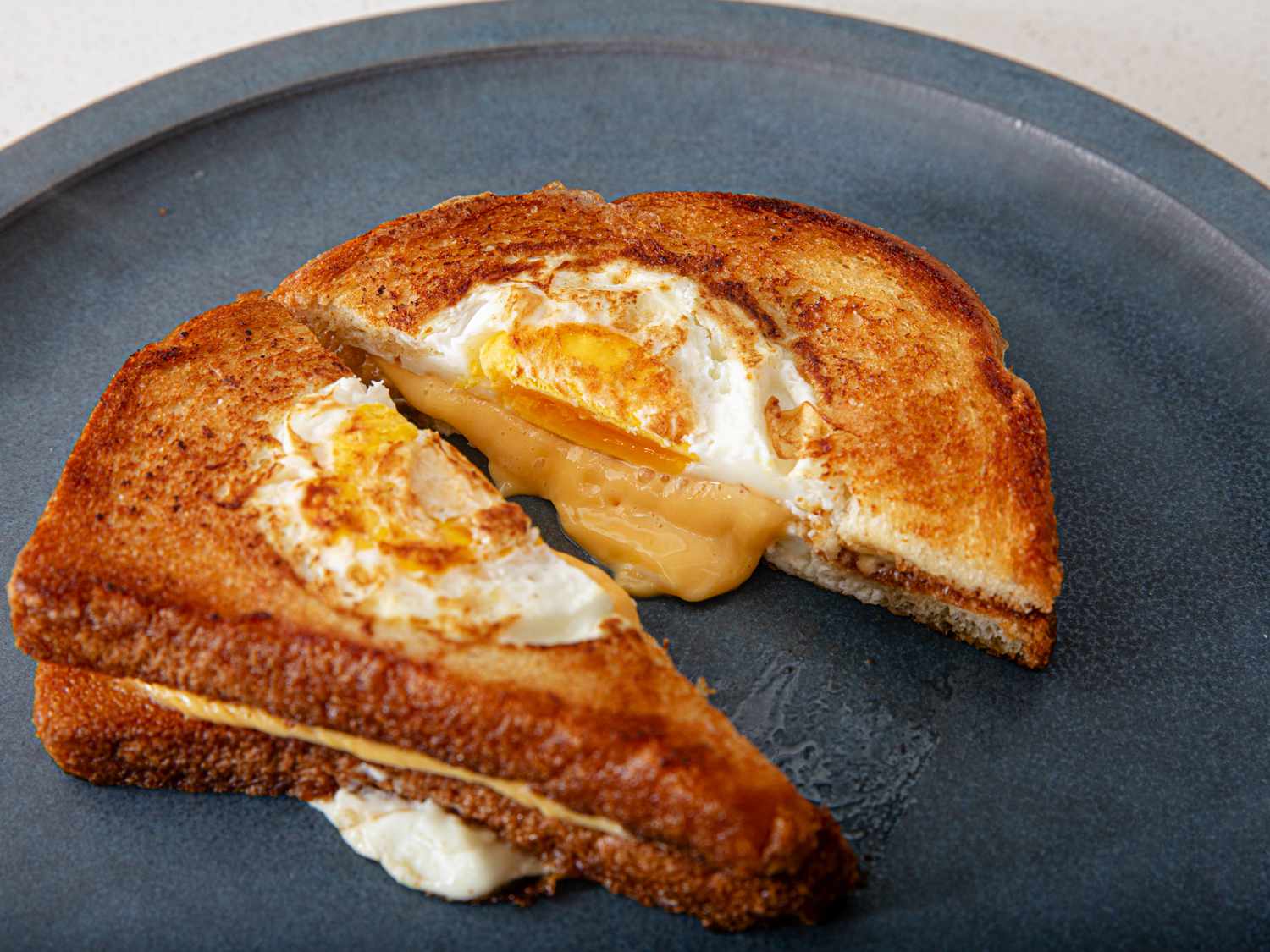 Grilled Cheese Eggplosion cut in half on a blue plate