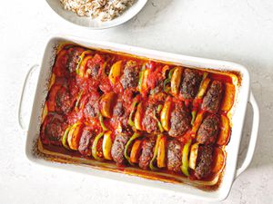 Overhead view of kafta in baking dish next to a bowl of rice.